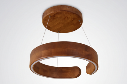 A modern wooden pendant light with a large circular ring shade and a smaller round ceiling canopy, suspended by thin cables against a plain white background.