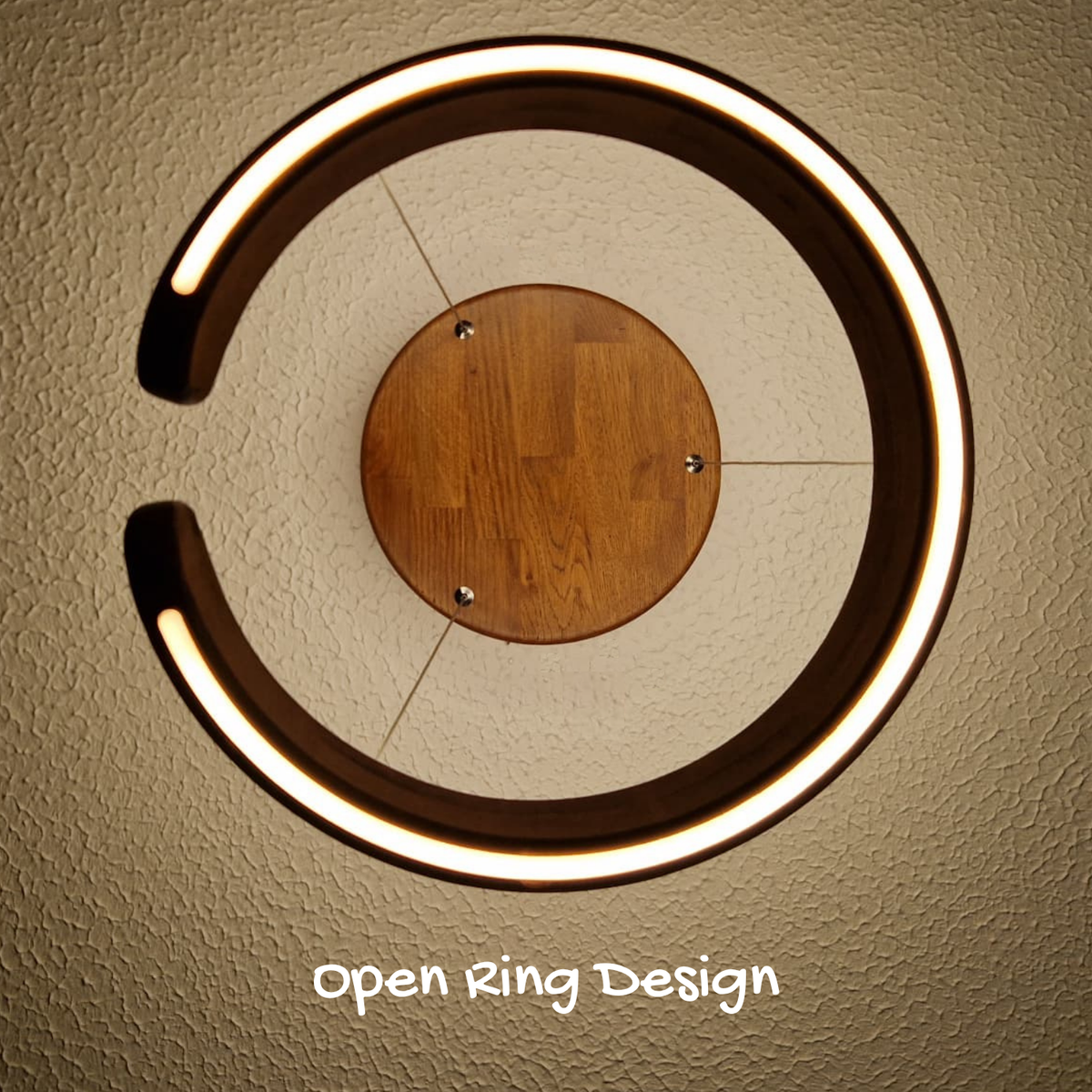 Top-down view of an open-ring LED wall light with a warm white illuminated circular frame and a central wooden disc, mounted on a textured beige wall, with the text 'Open Ring Design' below.