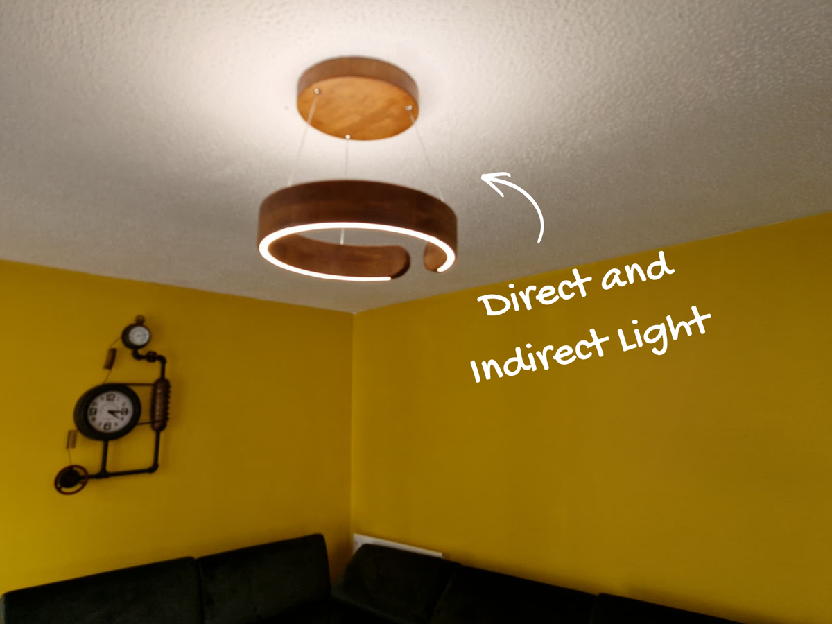 Oak ring pendant light installed above a corner sofa in a room with mustard yellow walls, showing direct and indirect lighting with handwritten text and an arrow reading 'Direct and Indirect Light'.