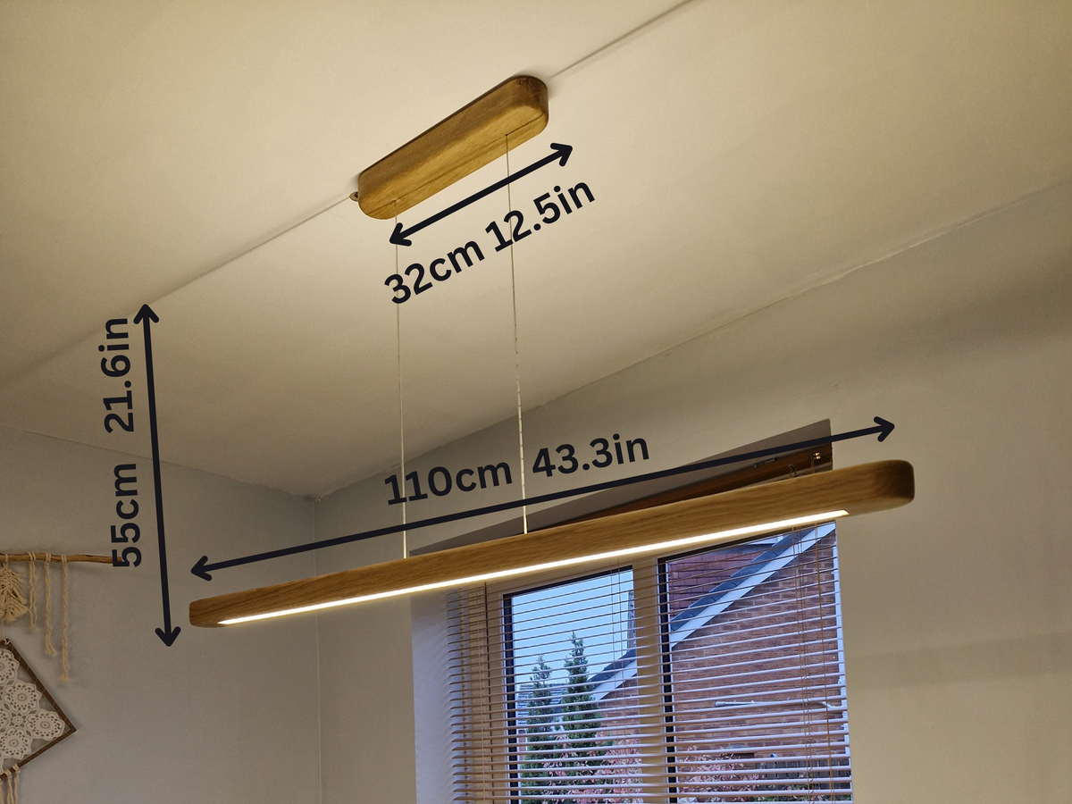 A linear LED ceiling light fixture with a wood-look finish, shown hanging in a room with overlaid dimension arrows and labels indicating 110cm length, 32cm width, and 55cm height.