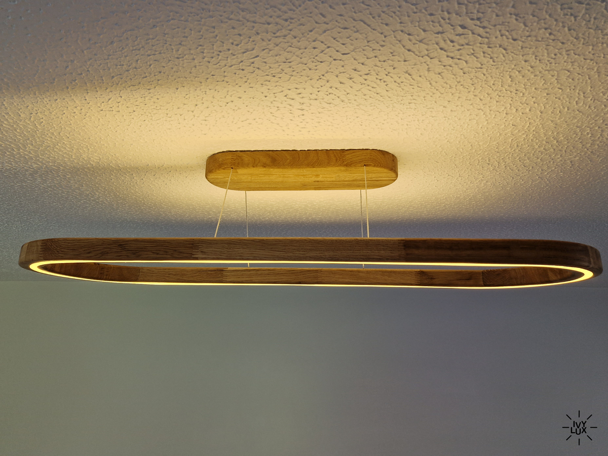A modern linear LED light fixture with a dark wood frame and a matching wood ceiling mount, shown illuminated against a textured white ceiling.