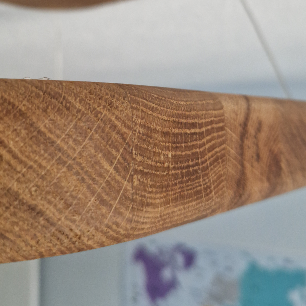 Close-up of a curved wooden bar or trim showing detailed wood grain and texture, with a blurred indoor background.