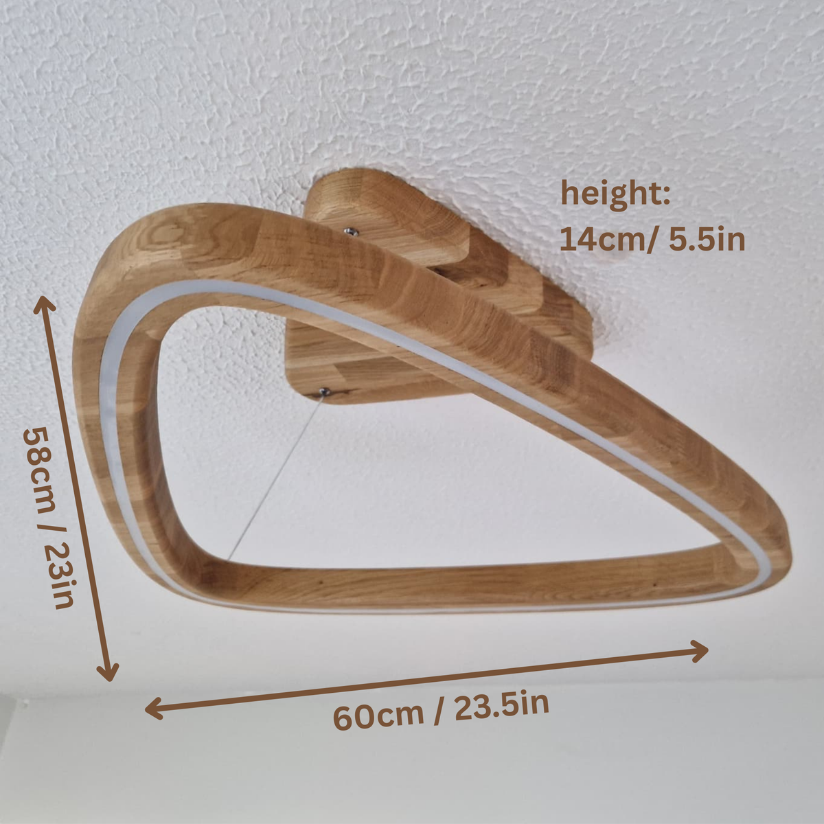 A triangular wooden pendant light frame shown with dimension measurements: 60cm/23.5in width, 58cm/23in height, and 14cm/5.5in depth, against a white textured wall.