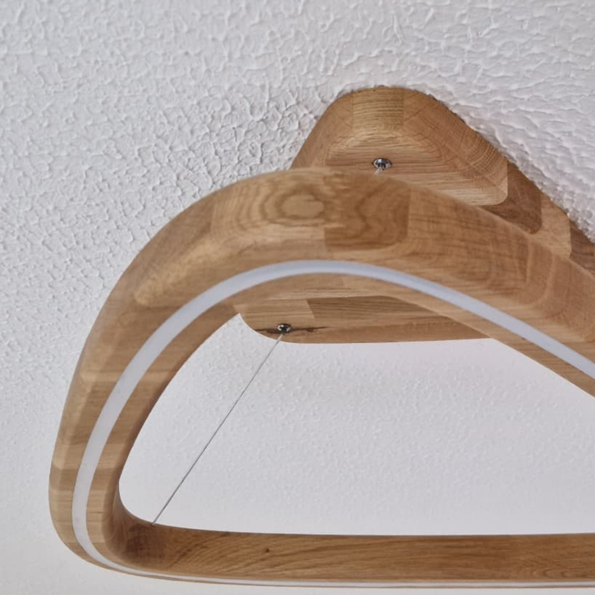 Close-up of a curved wooden ceiling-mounted pendant light fixture with a white LED strip, shown against a white textured ceiling.
