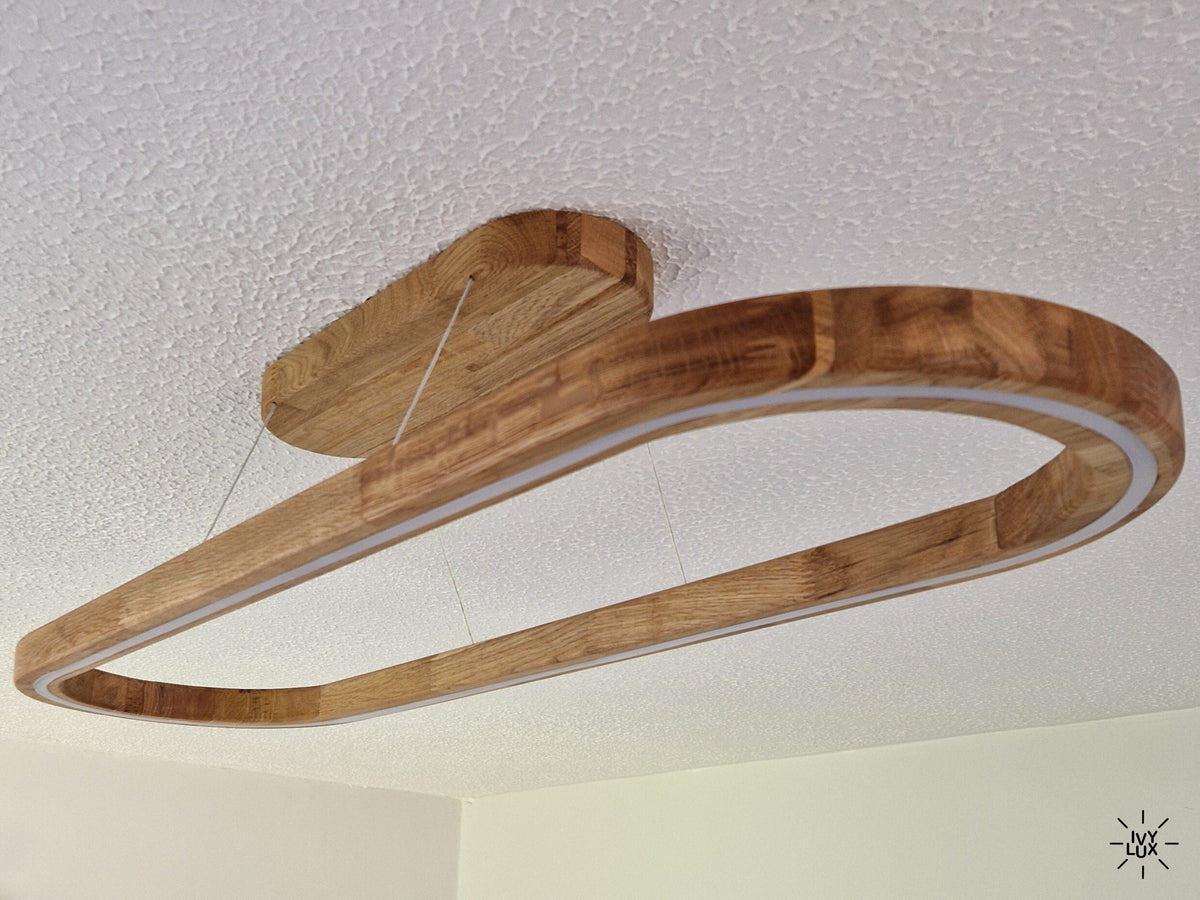 A modern linear LED ceiling light with a curved wooden frame, suspended from a matching wooden ceiling mount against a textured white ceiling.